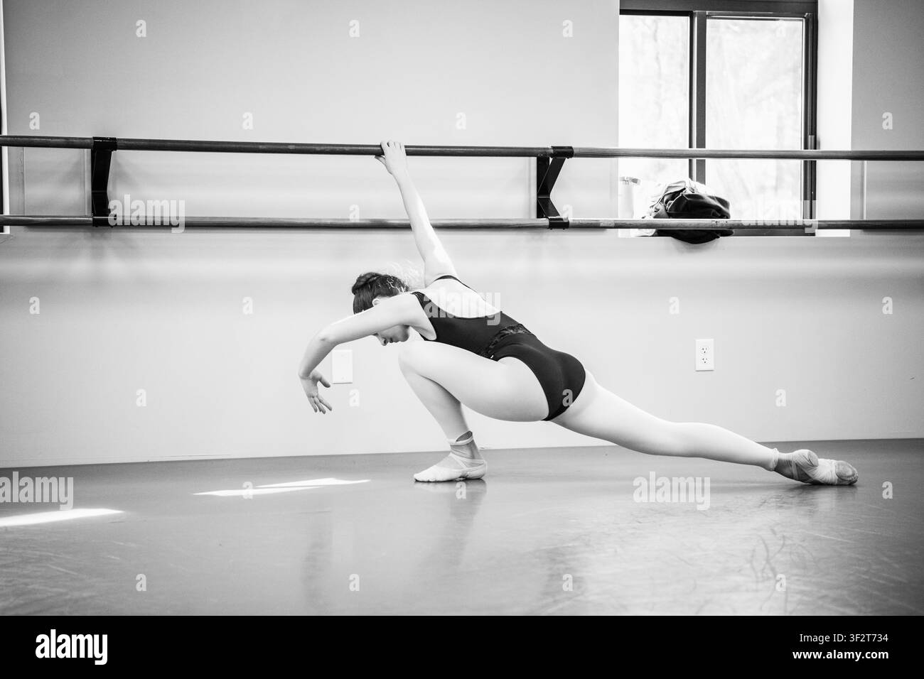 Dancer stretching at barre in black and white studio Stock Photo