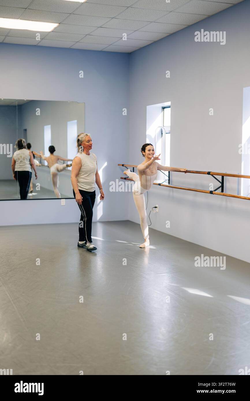 Ballet dancer practicing at barre with instructor Stock Photo