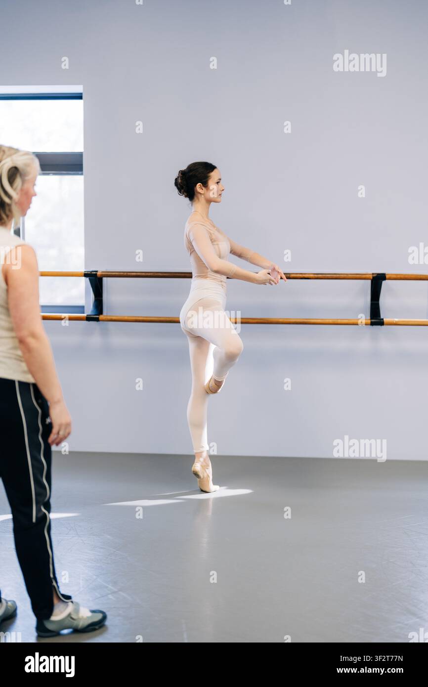 Ballerina practicing ballet at barre with instructor watching Stock Photo