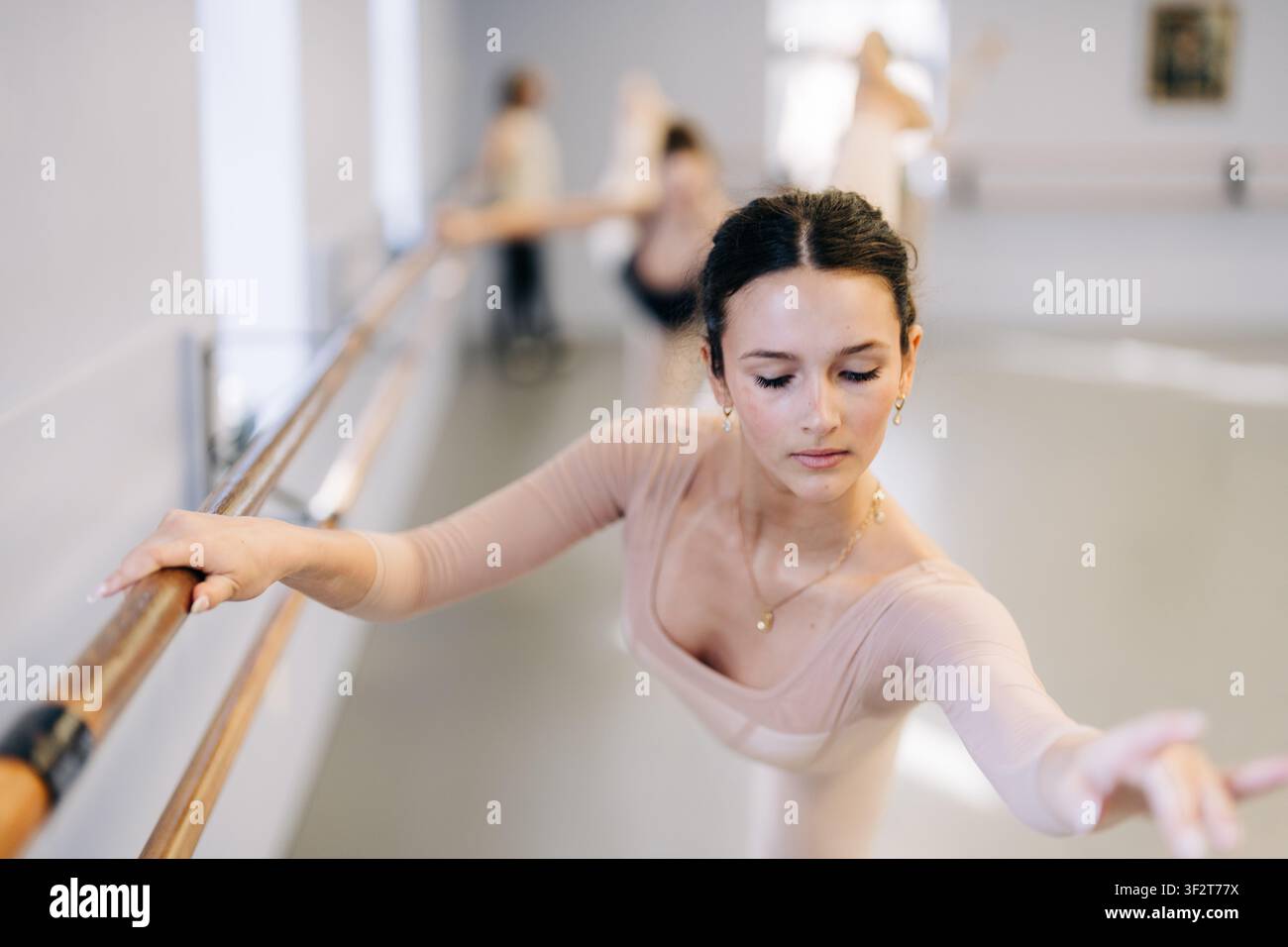 Young ballerina practicing graceful barre exercise in dance studio Stock Photo