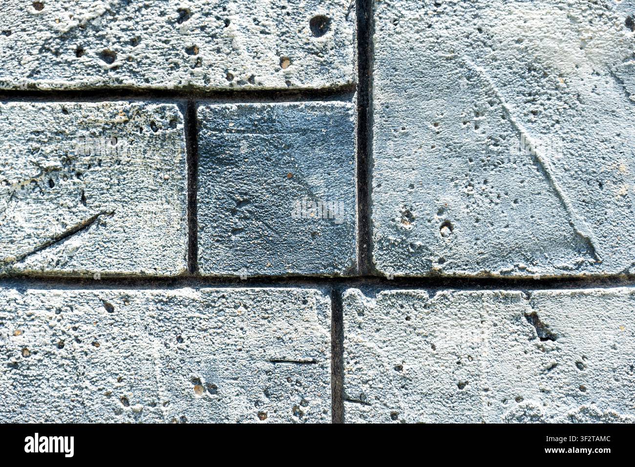 Close-up of textured grey stone blocks with pitted surface. Modern architectural background for construction and urban design projects Stock Photo