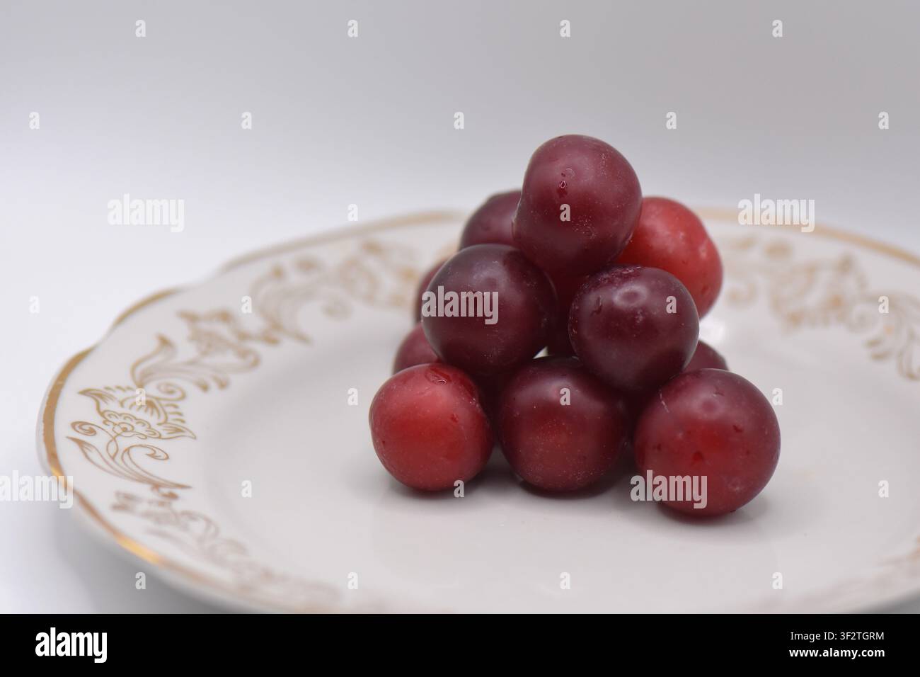 Plate with overripe cherry plums on a white background. Isolated Stock Photo