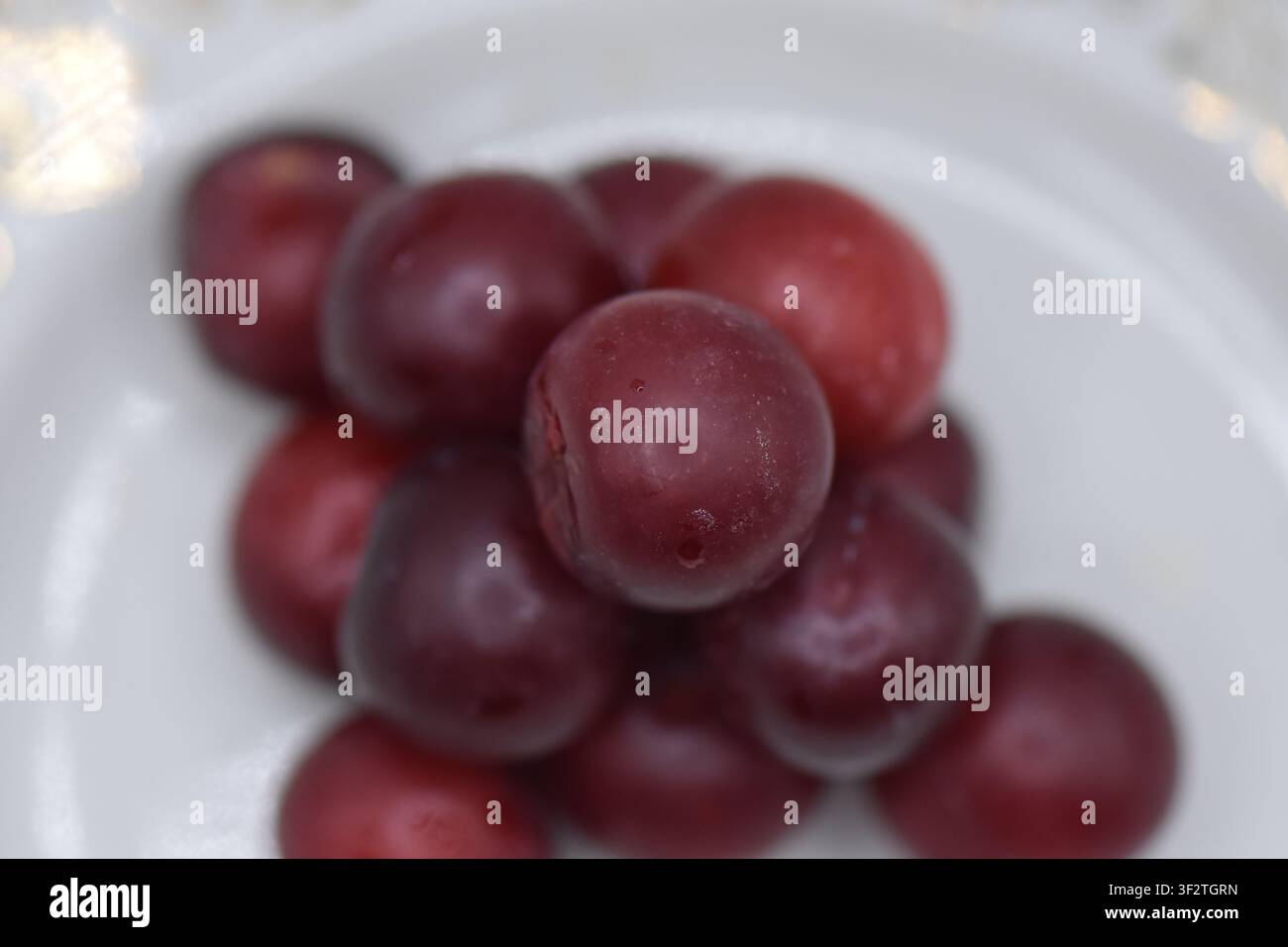 Plate with overripe cherry plums on a white background. Isolated Stock Photo