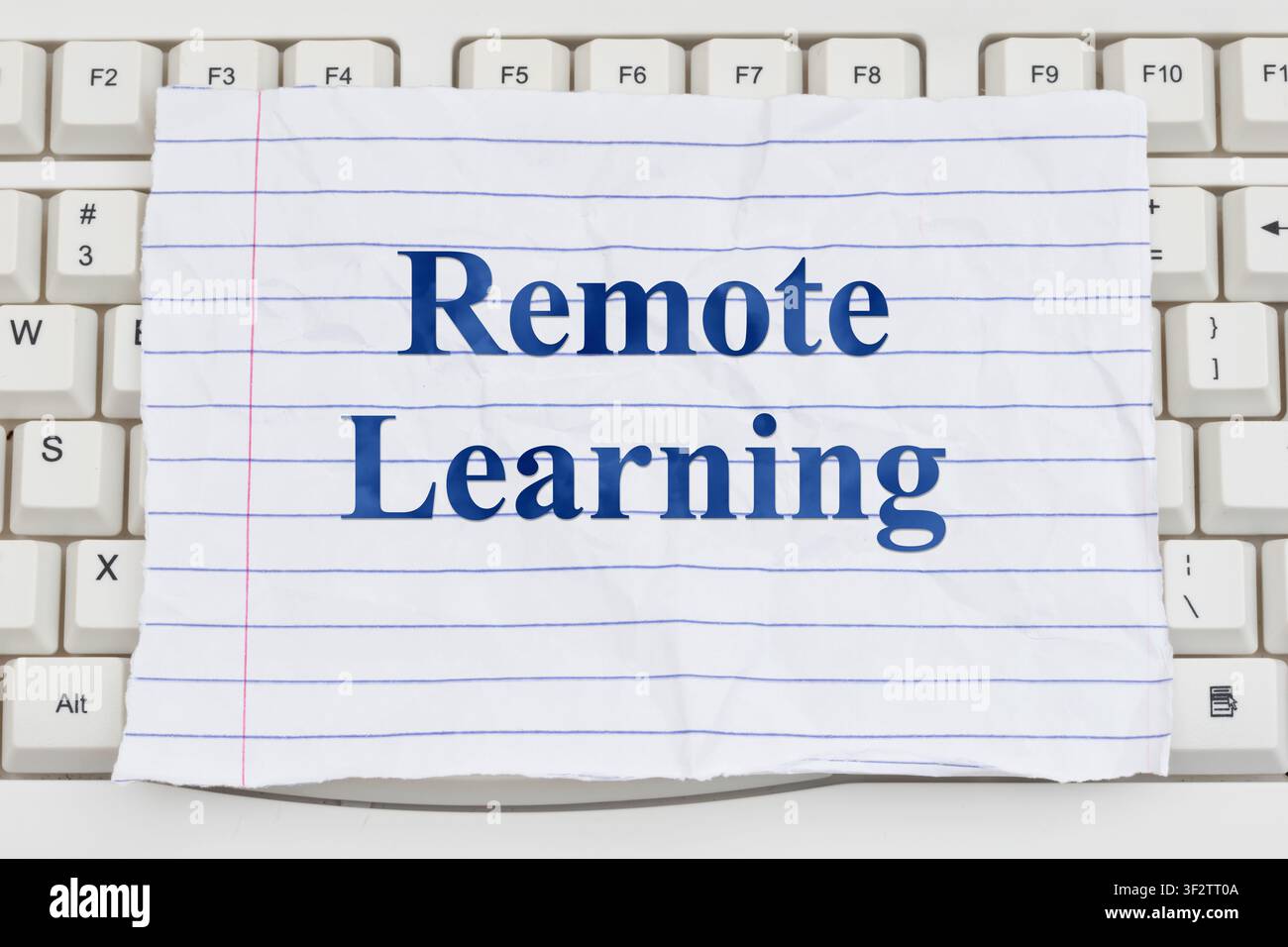 Remote Learning text on ripped lined paper on a white computer keyboard for online courses and e-learning Stock Photo