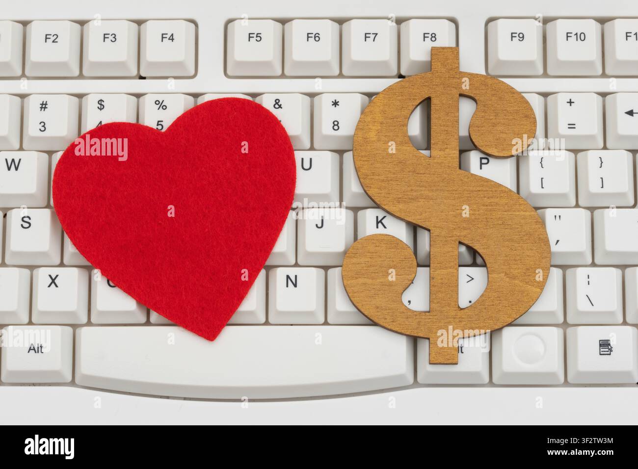 Blank red heart with a dollar sign on a white computer keyboard for online romance scams Stock Photo