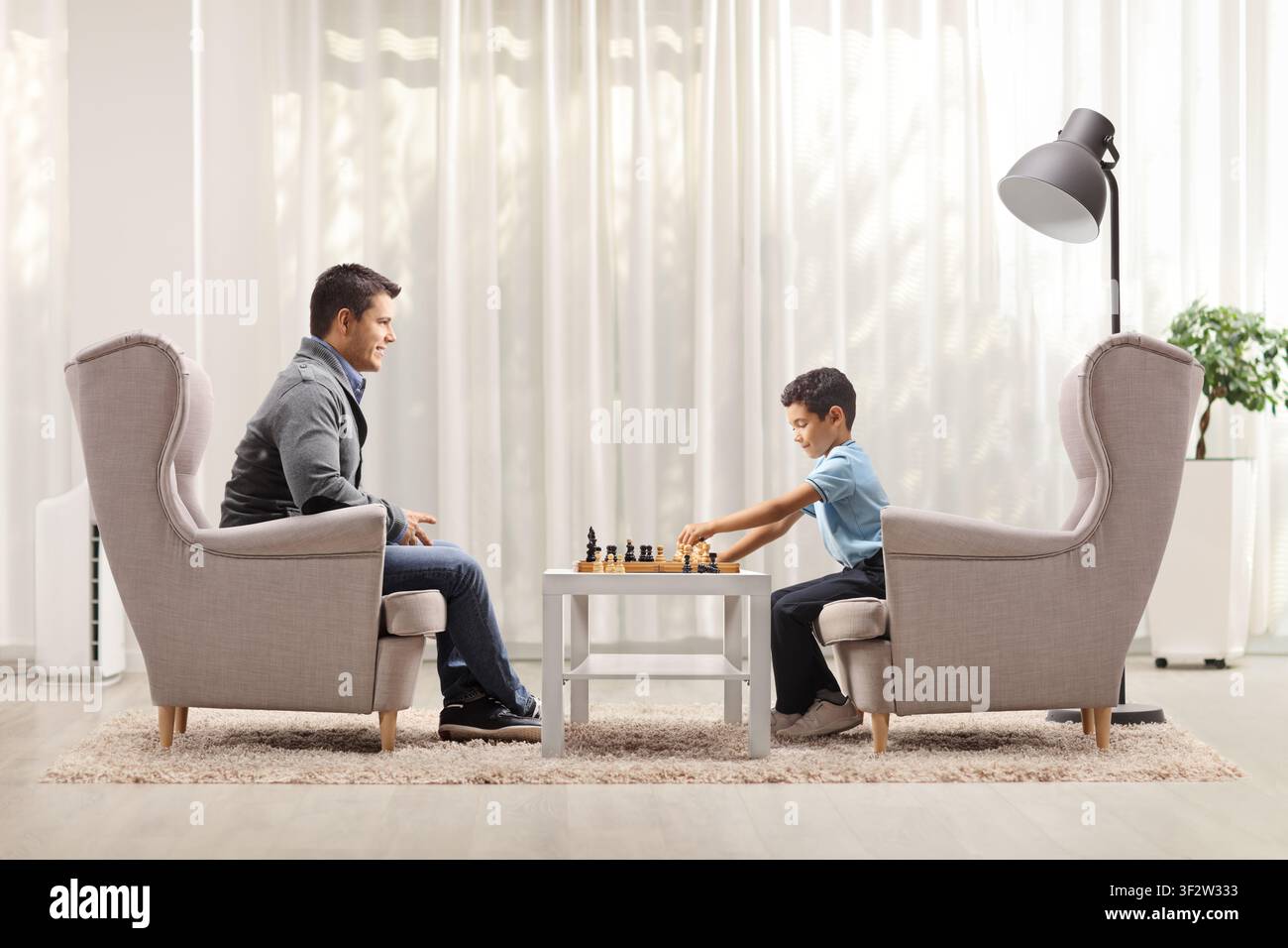 Father and son playing chess and sitting in armchairs Stock Photo