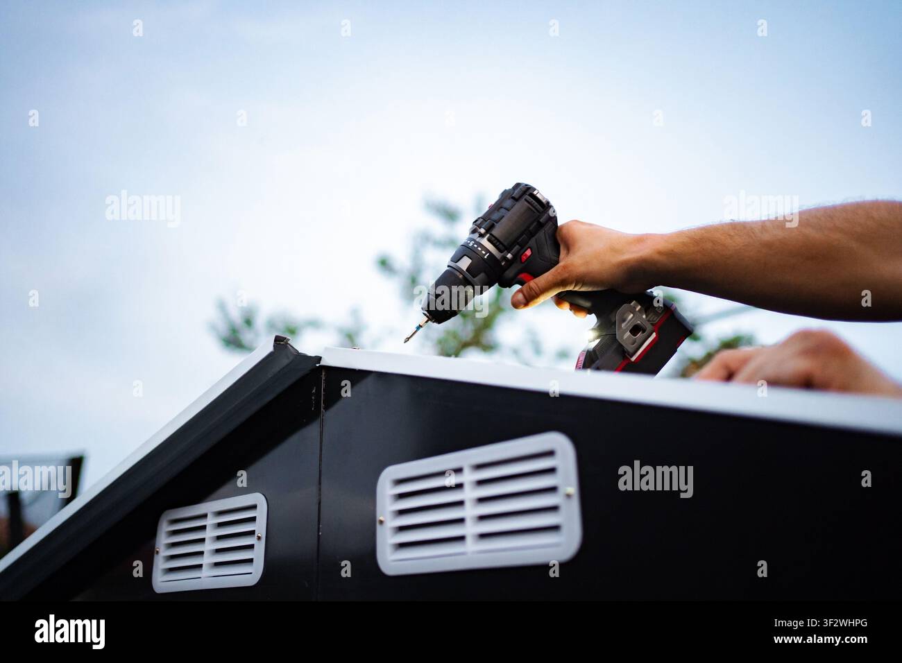 Man installing roof panel using cordless power drill Stock Photo