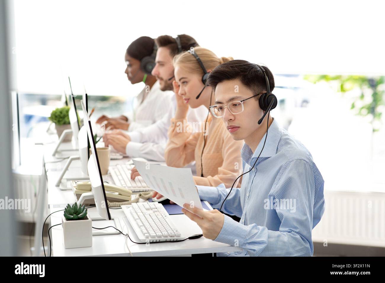Asian hotline operator working with documents, providing technical support services to clients, free space Stock Photo