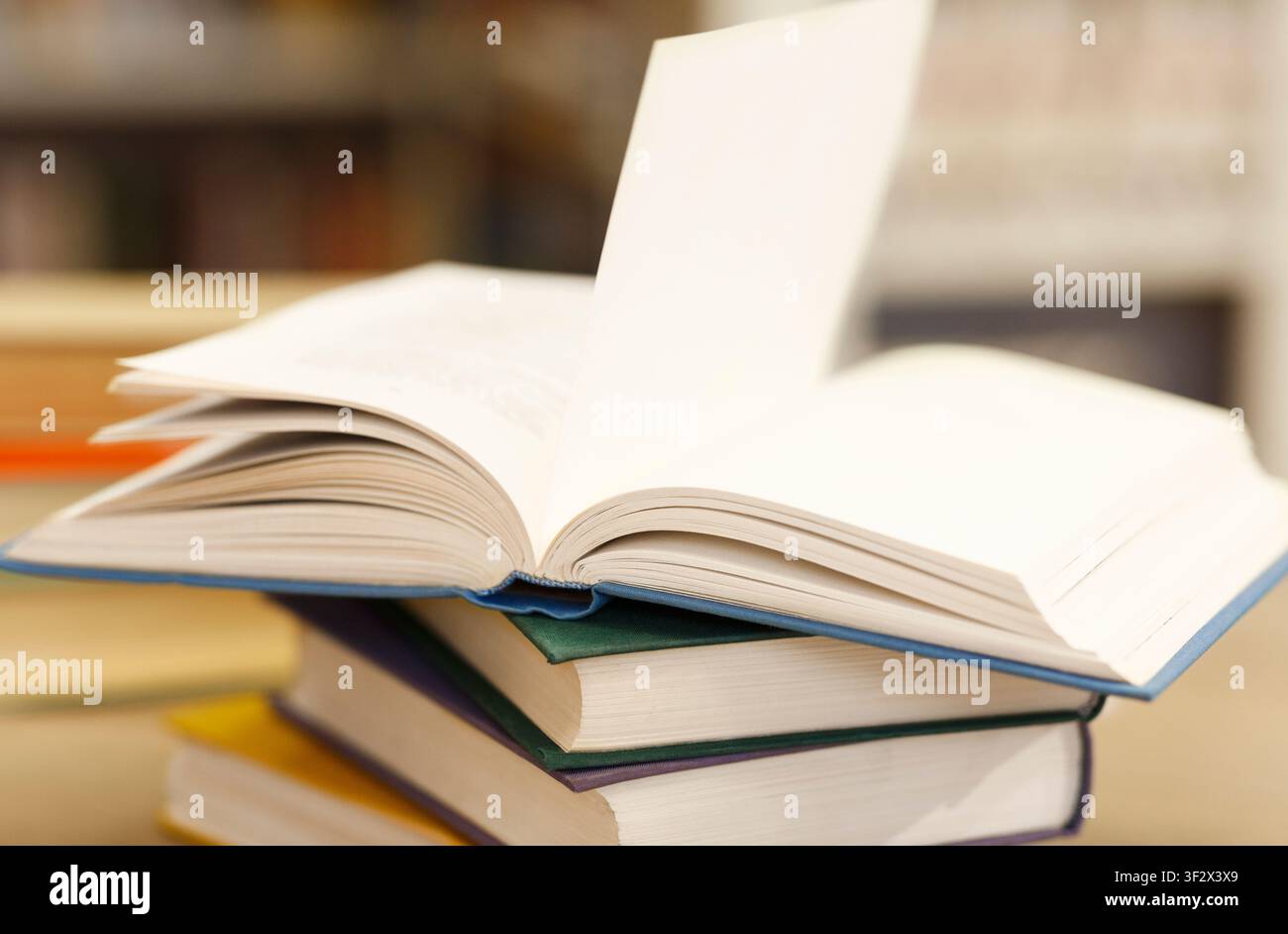 Open book lying on a stack of manuals Stock Photo