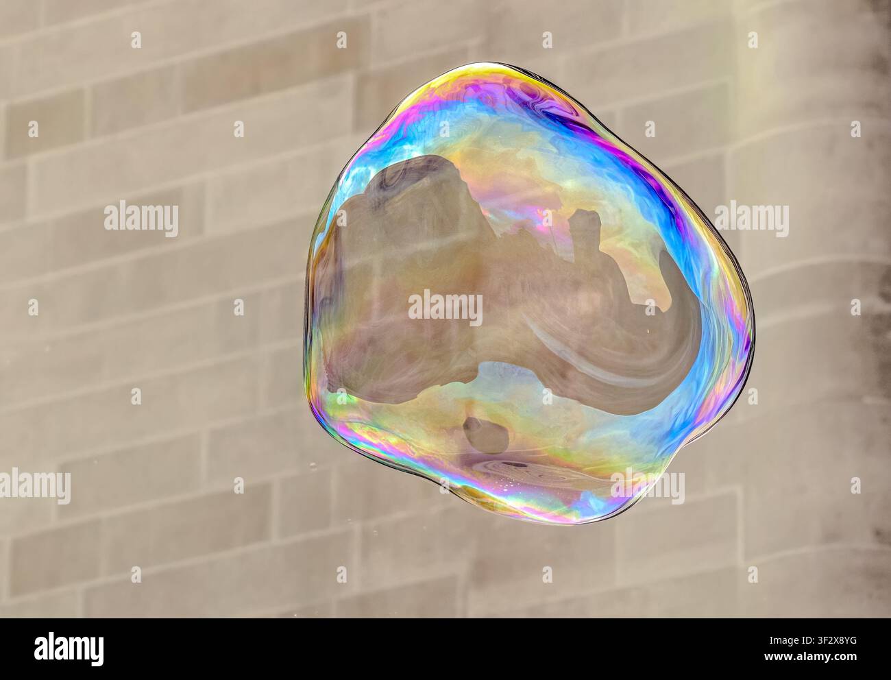 Iridescent soap bubble floating against a soft neutral background Stock Photo