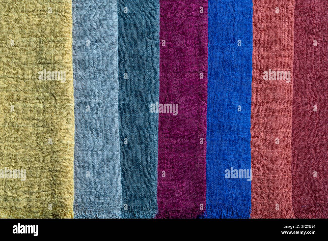 Assortment of multi colored organic linen or cotton textile swatches arranged in vertical lines, close up. Canvas woven material fabric palette backgr Stock Photo