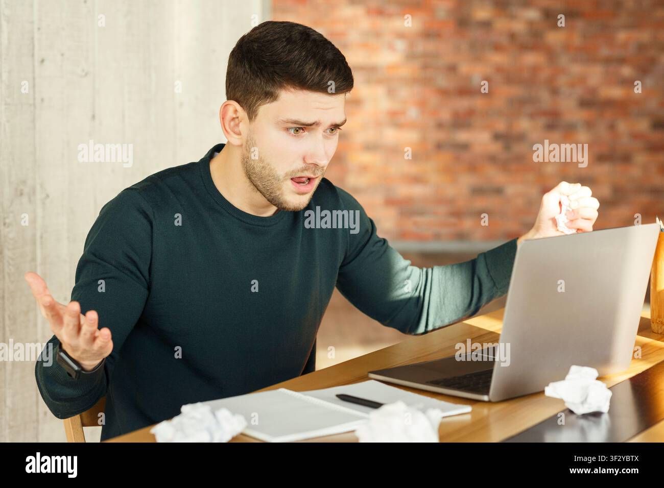 Emotional Worker Looking At Laptop Having Problem Sitting In Office Stock Photo