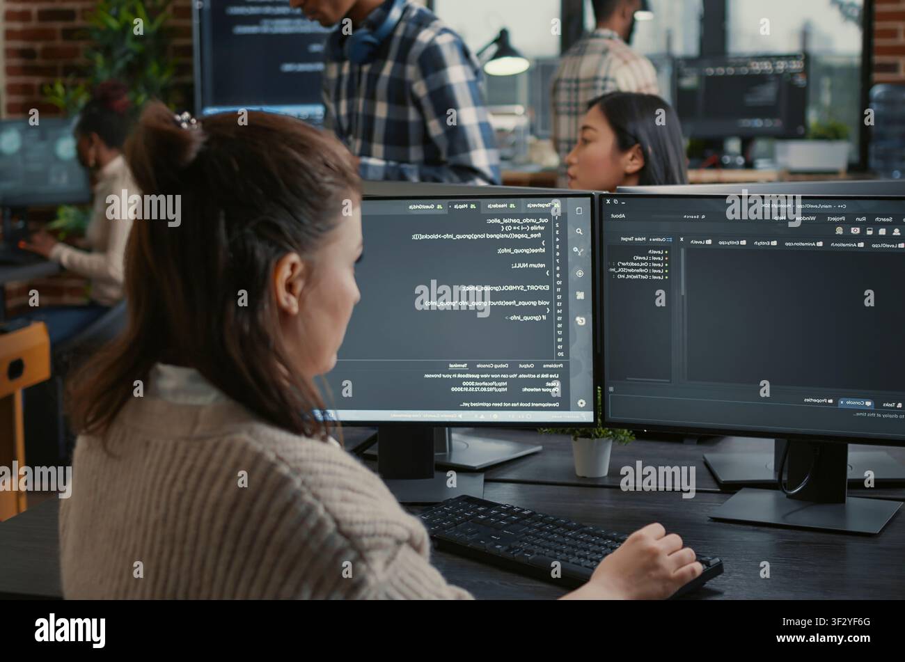 Software programmer writes database code in front of multiple screens showing artificial intelligence algorithms, while colleagues collaborate on cloud computing work. Stock Photo