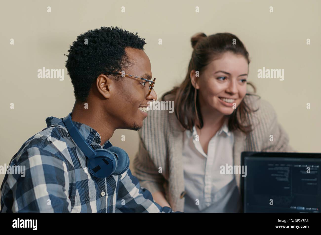 System engineers celebrate successful code compilation with a high five, congratulating a coworker while analyzing algorithms on multiple computer screens. Stock Photo
