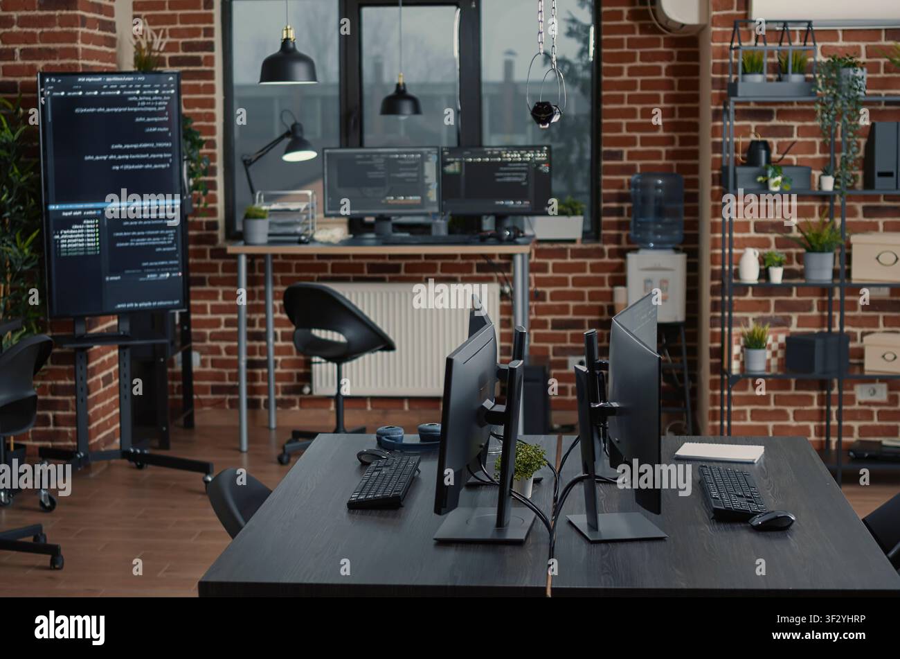 Empty software IT agency office and computers in background with multiple monitors, programming code and cloud computing visuals inside an empty software agency workspace. Stock Photo