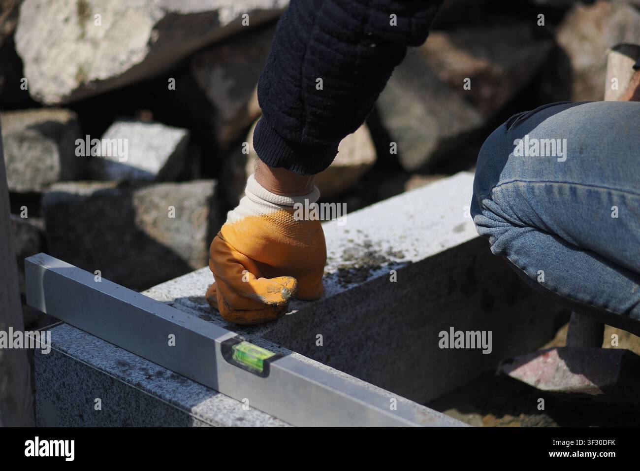 Construction worker uses level tool outdoors on a project Stock Photo