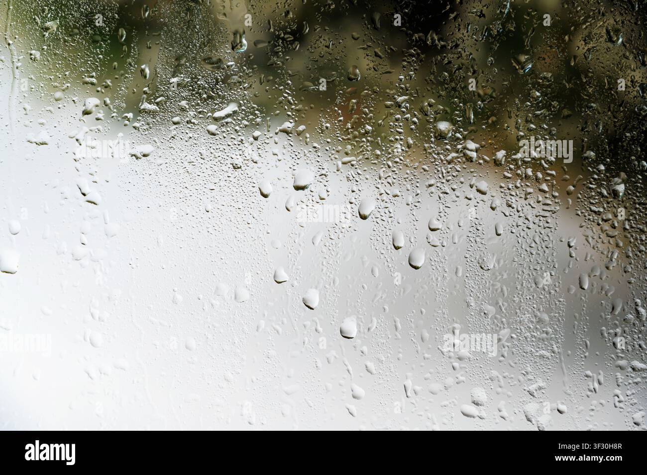 A close-up view of a gray painted surface featuring vertical liquid streaks and drips, creating a grunge industrial background for design projects Stock Photo