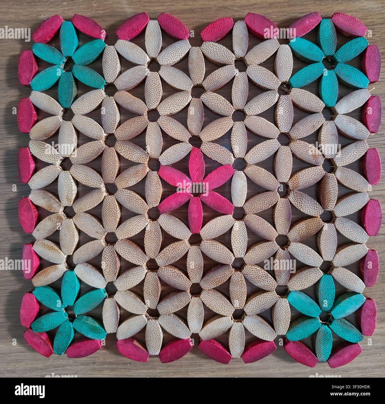 Heat resistant wooden coaster trivet with colorful flower bead patterns, perfect for protecting dining tables from hot pots, plates, and cups. Stock Photo