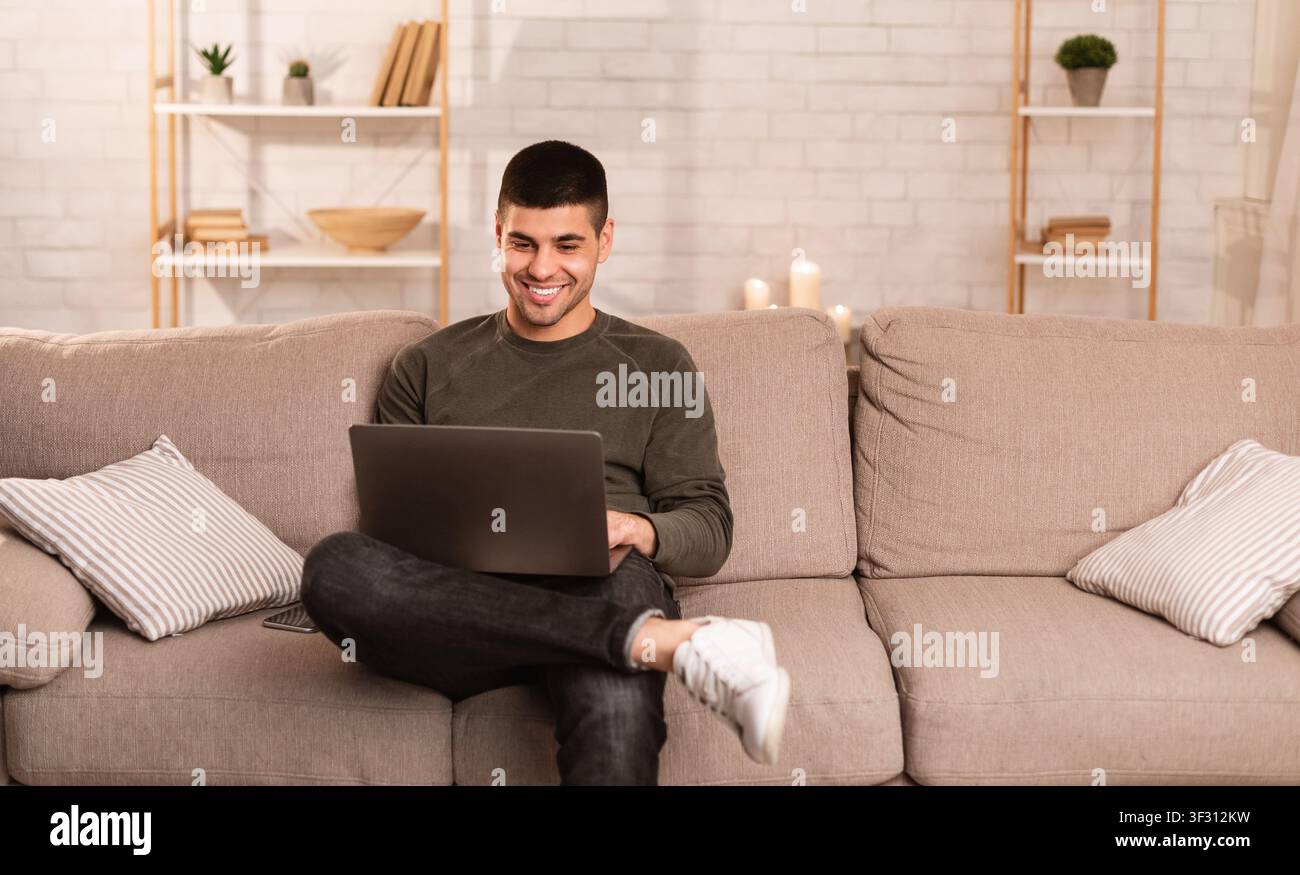 Man using his laptop sitting on sofa Stock Photo