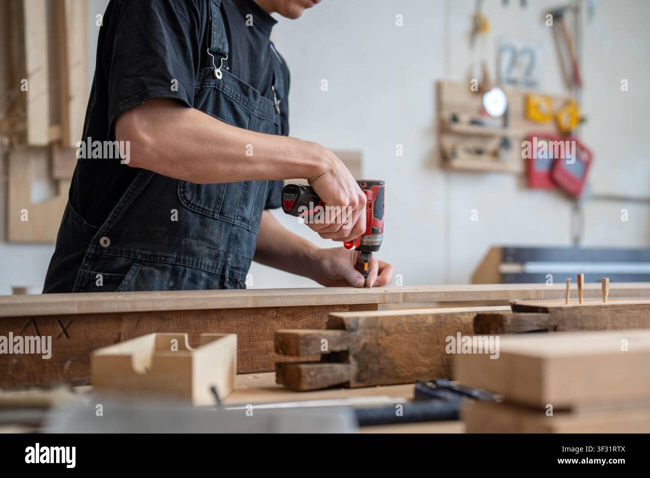 Craftsman technician working in restoration workshop, using professional cordless impact driver tool Stock Photo