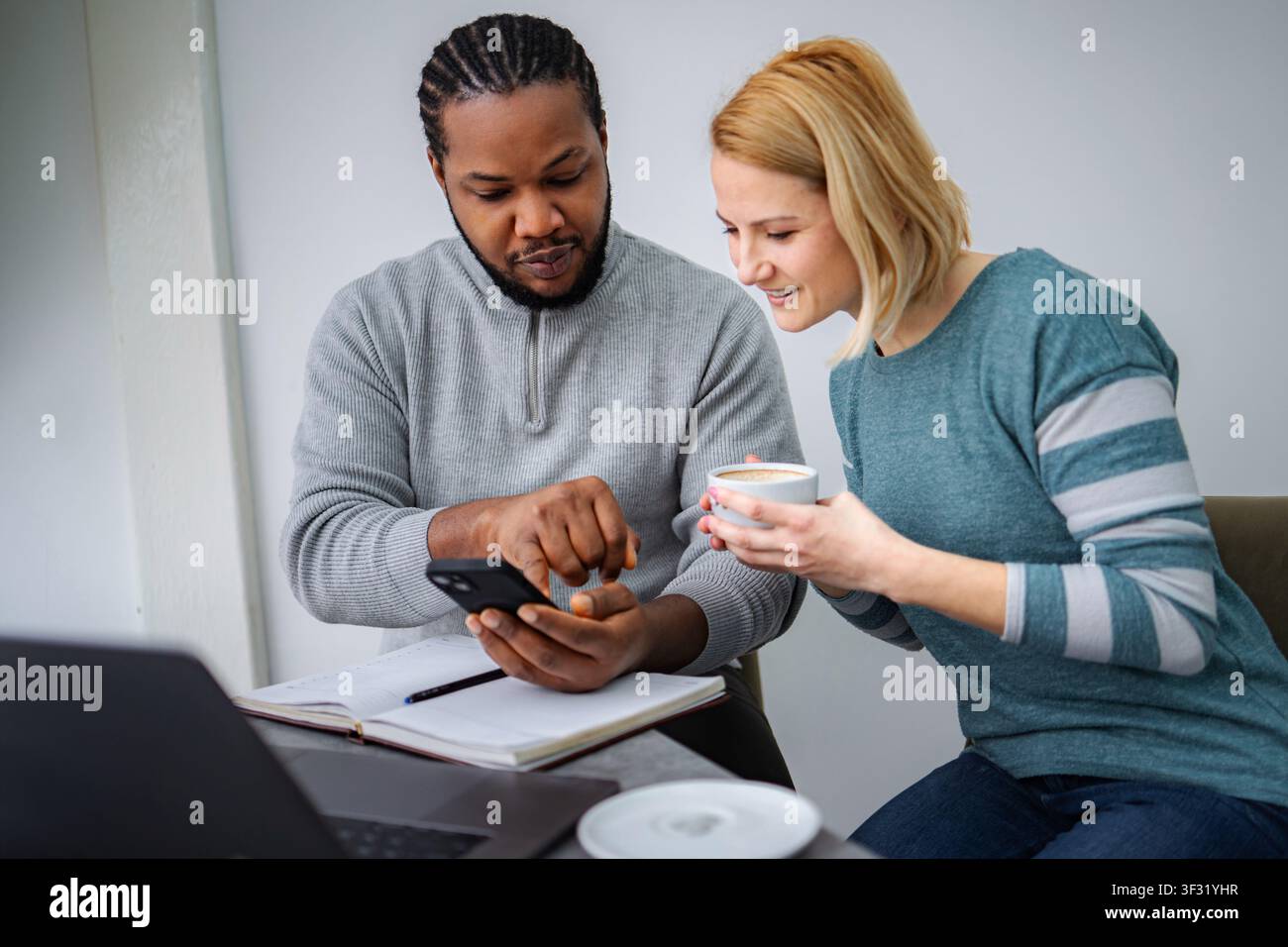 Diverse colleagues collaborating, discussing content on a smartphone Stock Photo