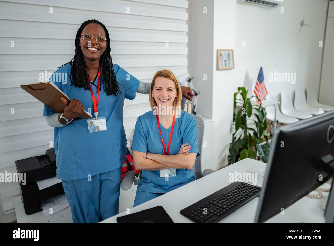 Diverse nurses standing together smiling in medical reception area Stock Photo