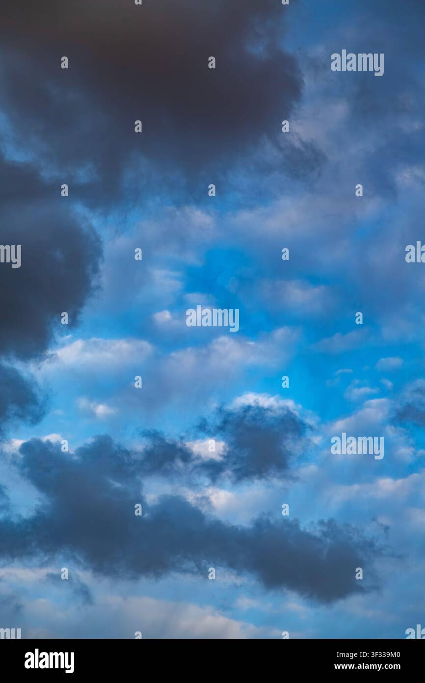Vertical dramatic sky with dark storm clouds framing a bright vivid blue center. Stock Photo