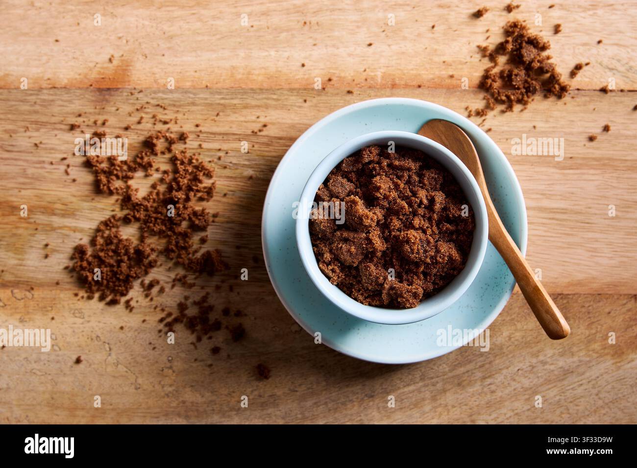 Dark muscovado sugar in a bowl with wooden spoon on rustic wooden table. Natural unrefined muscovado sugar for baking and cooking. Stock Photo