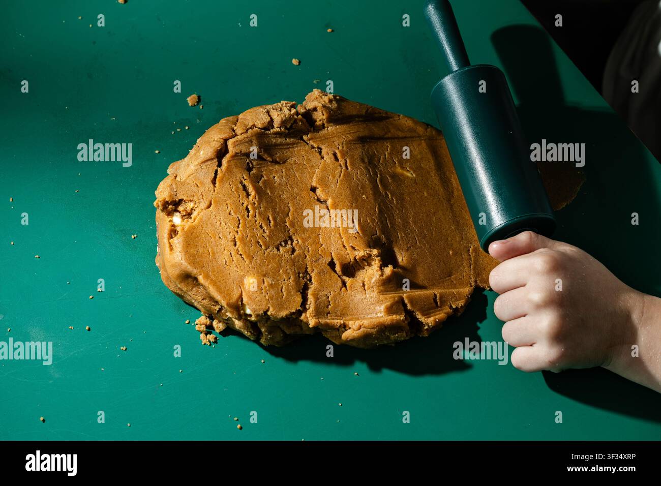 Child Preparing Gingerbread Cookie Dough with Rolling Pin on Green Table Stock Photo