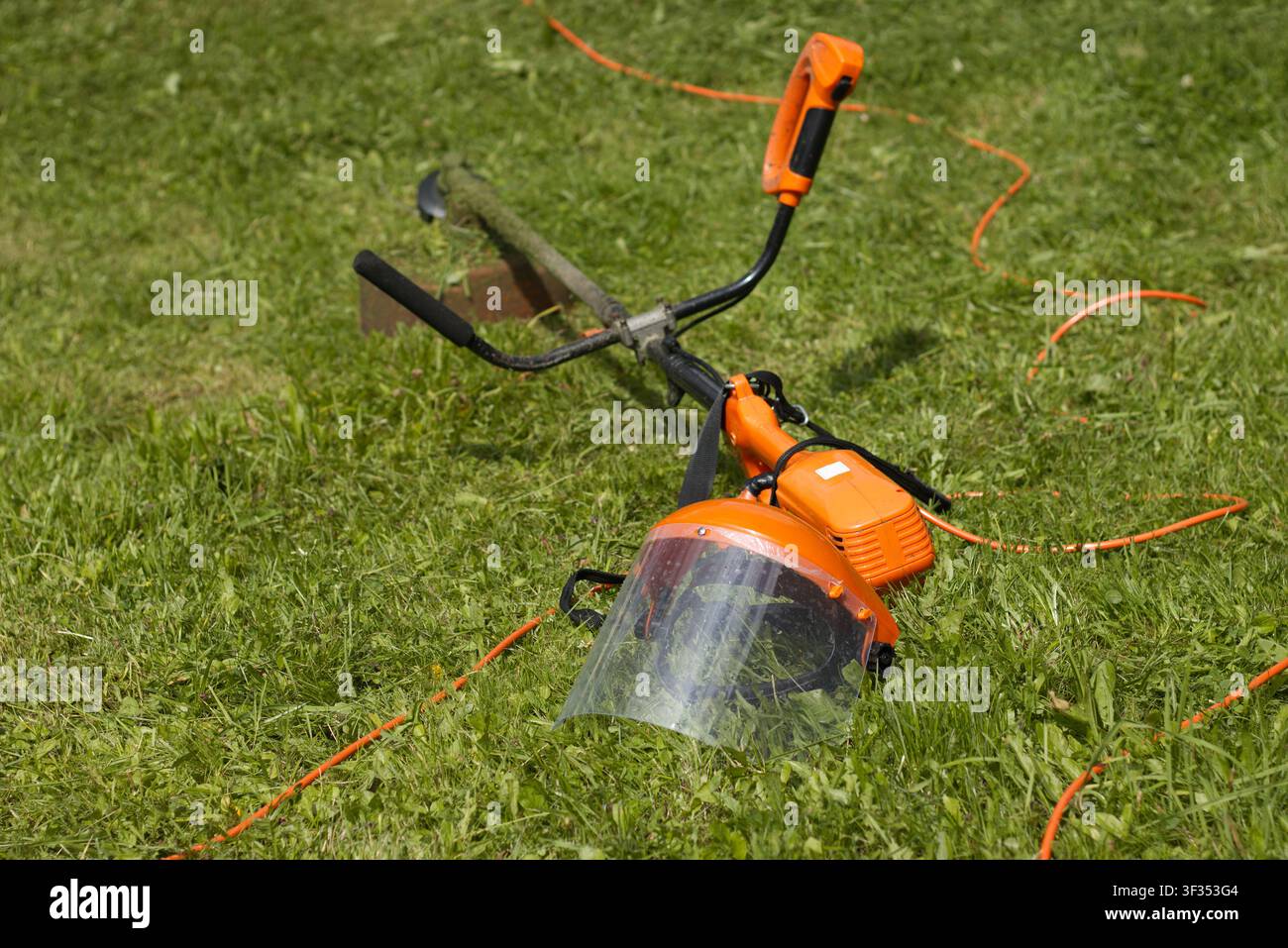 Grass trimmer and protective face shield on lawn Stock Photo