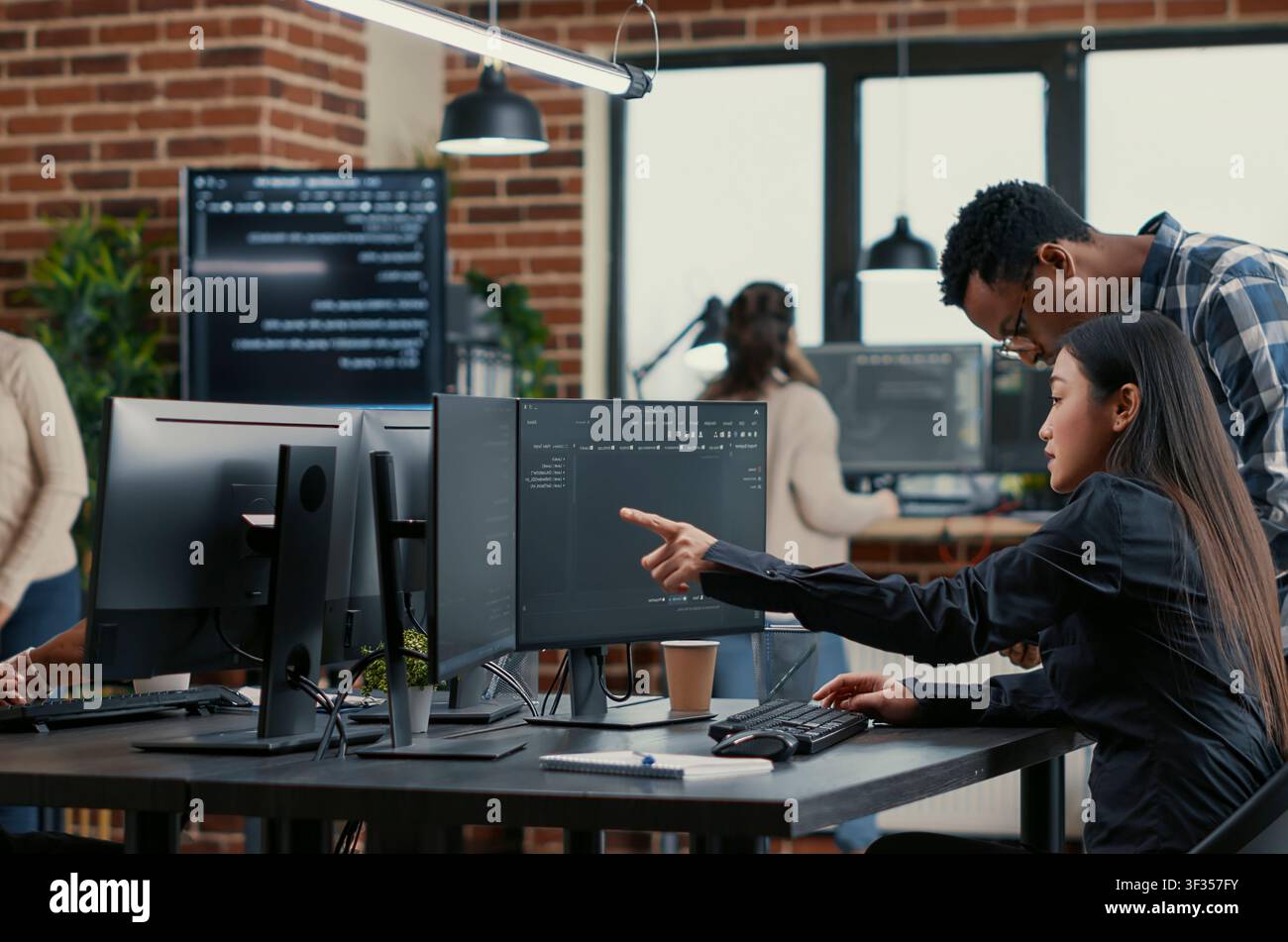Collaborative team of software developers reviewing source code pointing around computer screens, showing developer teamwork, source code discussion and cloud programming workflow. Stock Photo