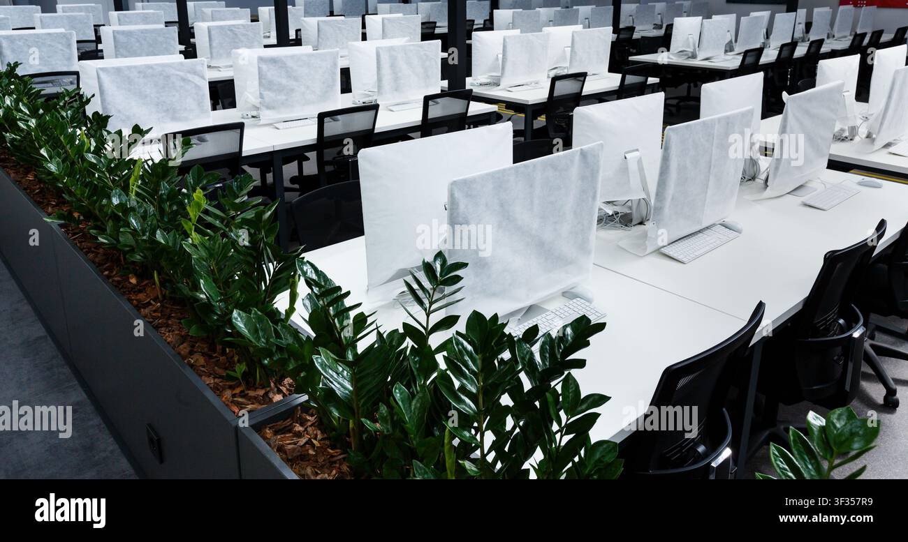 Wrapped in cover computers on workplaces with no people Stock Photo