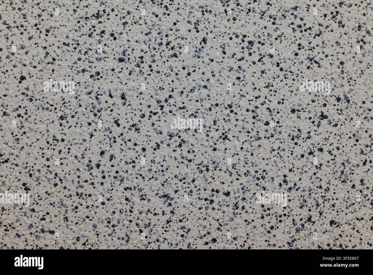 Speckled abstract wall showing uniform gray texture and black dots pattern Stock Photo