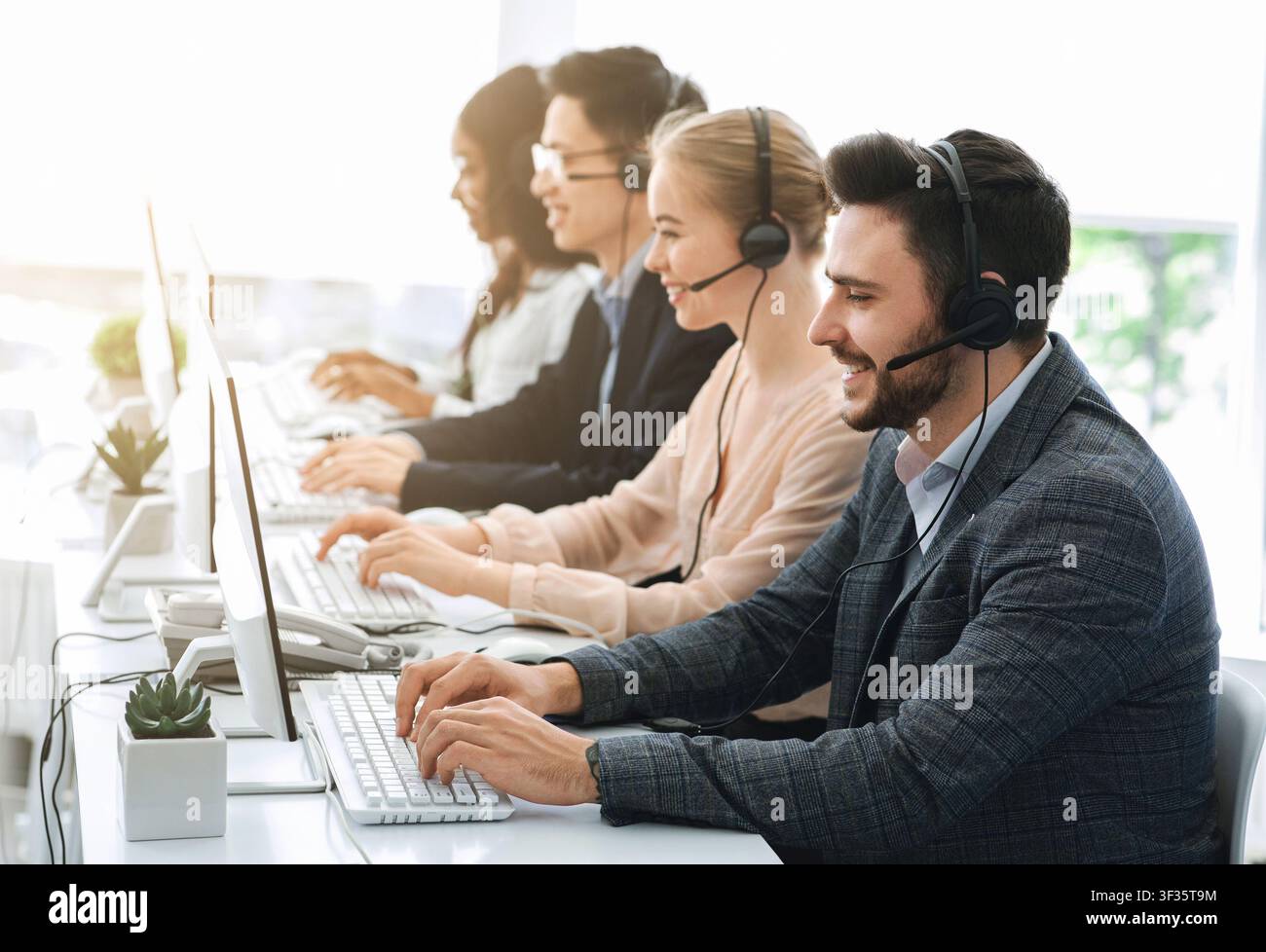 Telemarketing or hotline operators working with computers at light office Stock Photo