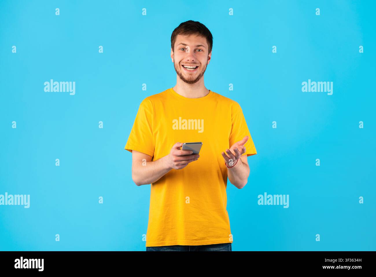 Smiling young man using mobile phone at studio Stock Photo