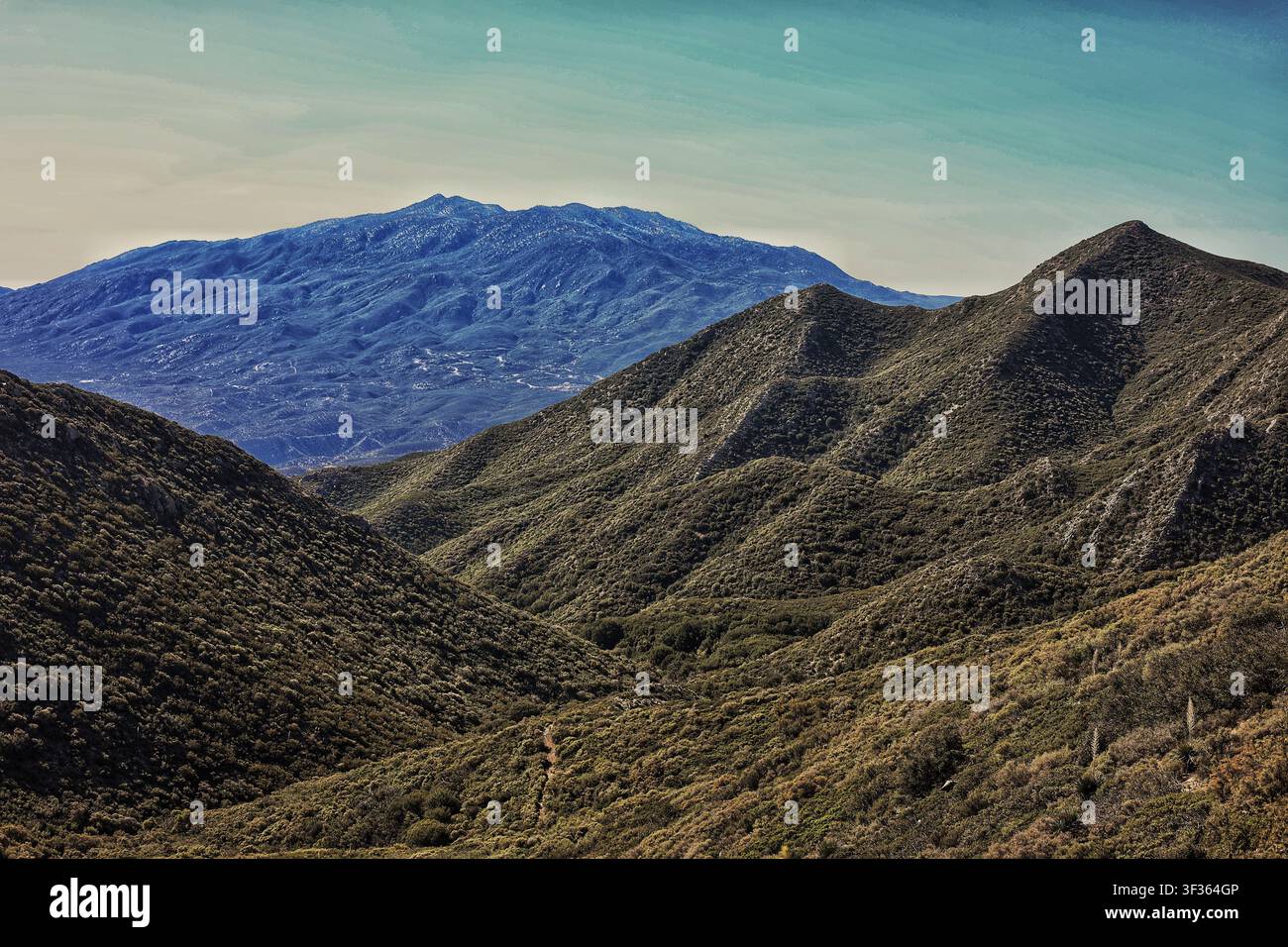 Layered Mountain Ridges Overlooking Blue Distant Peak Stock Photo