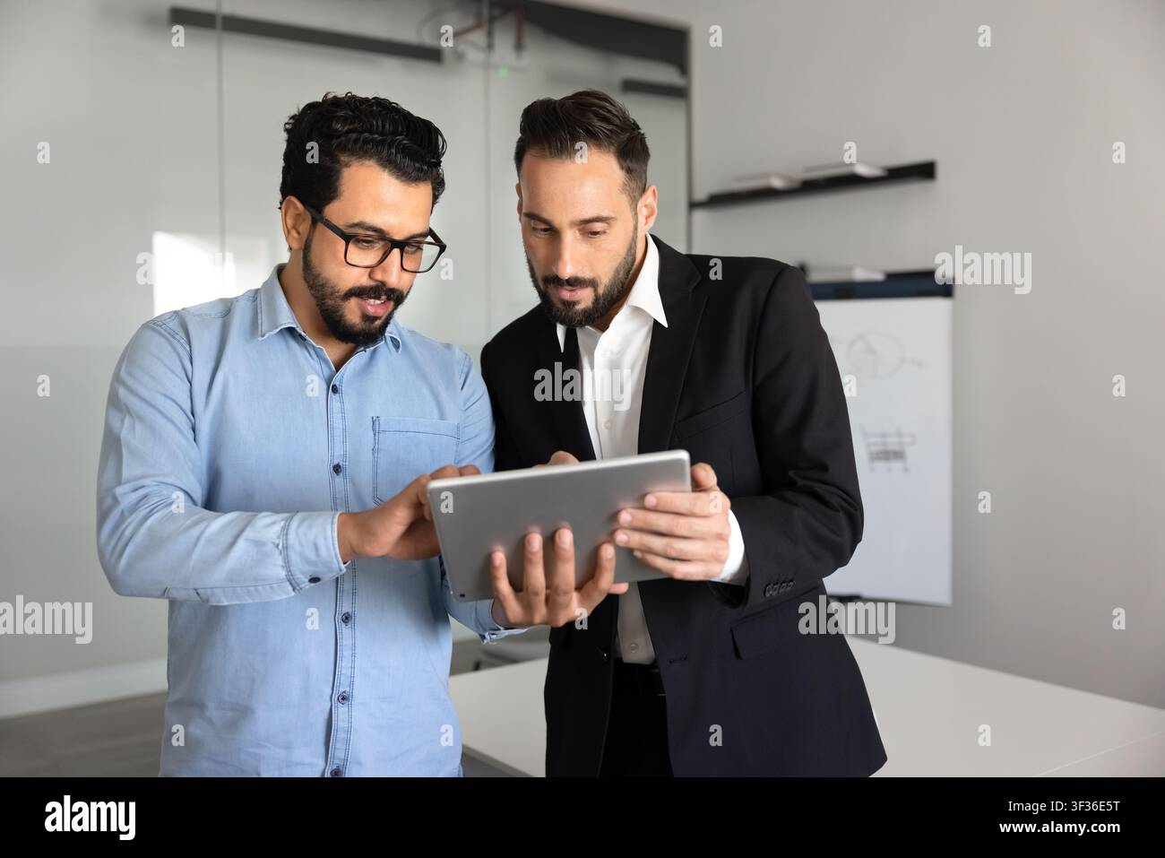 Two multiethnic male colleagues working on project using digital tablet Stock Photo
