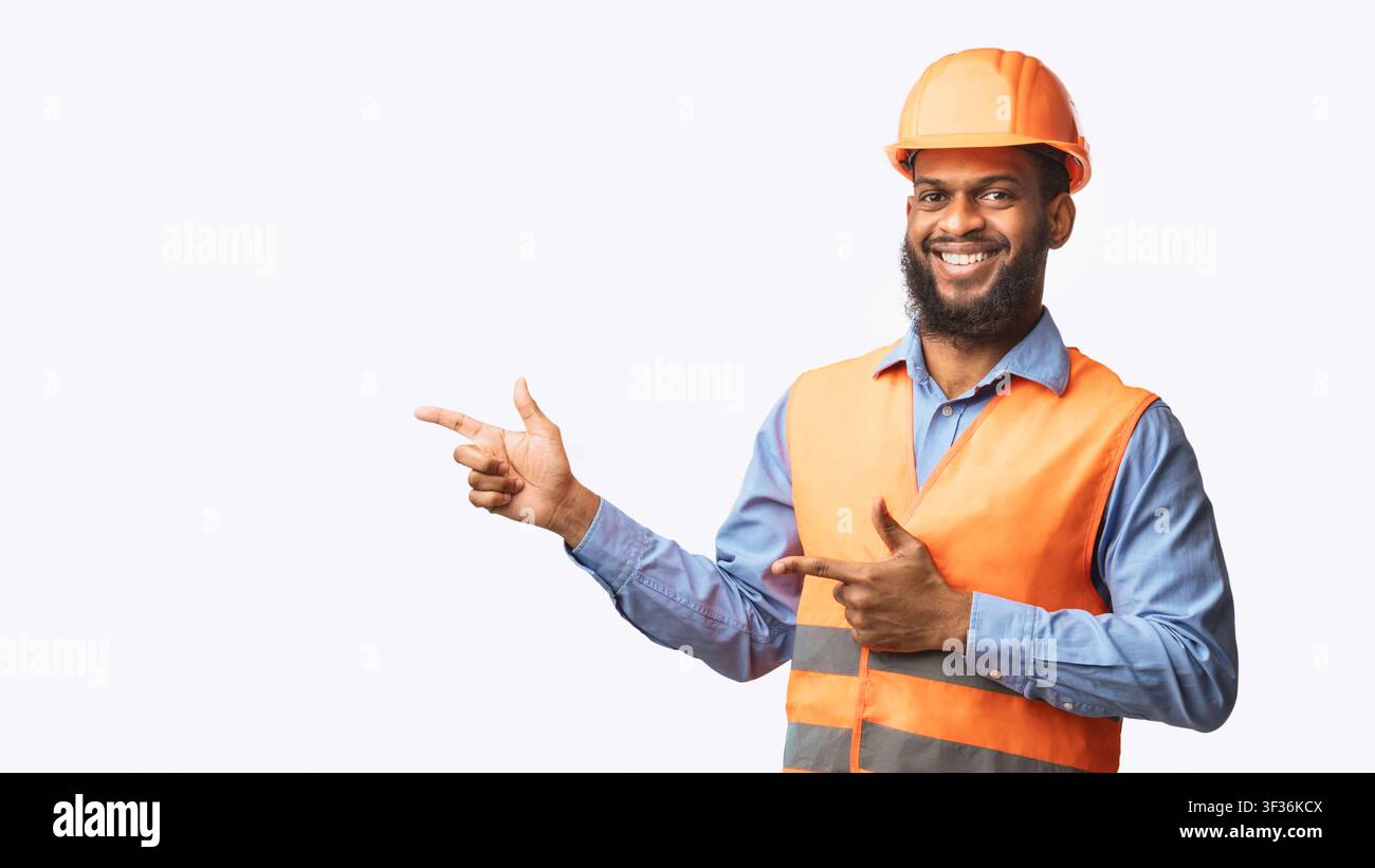 Builder Guy In Uniform Pointing Fingers Aside On White Background Stock Photo