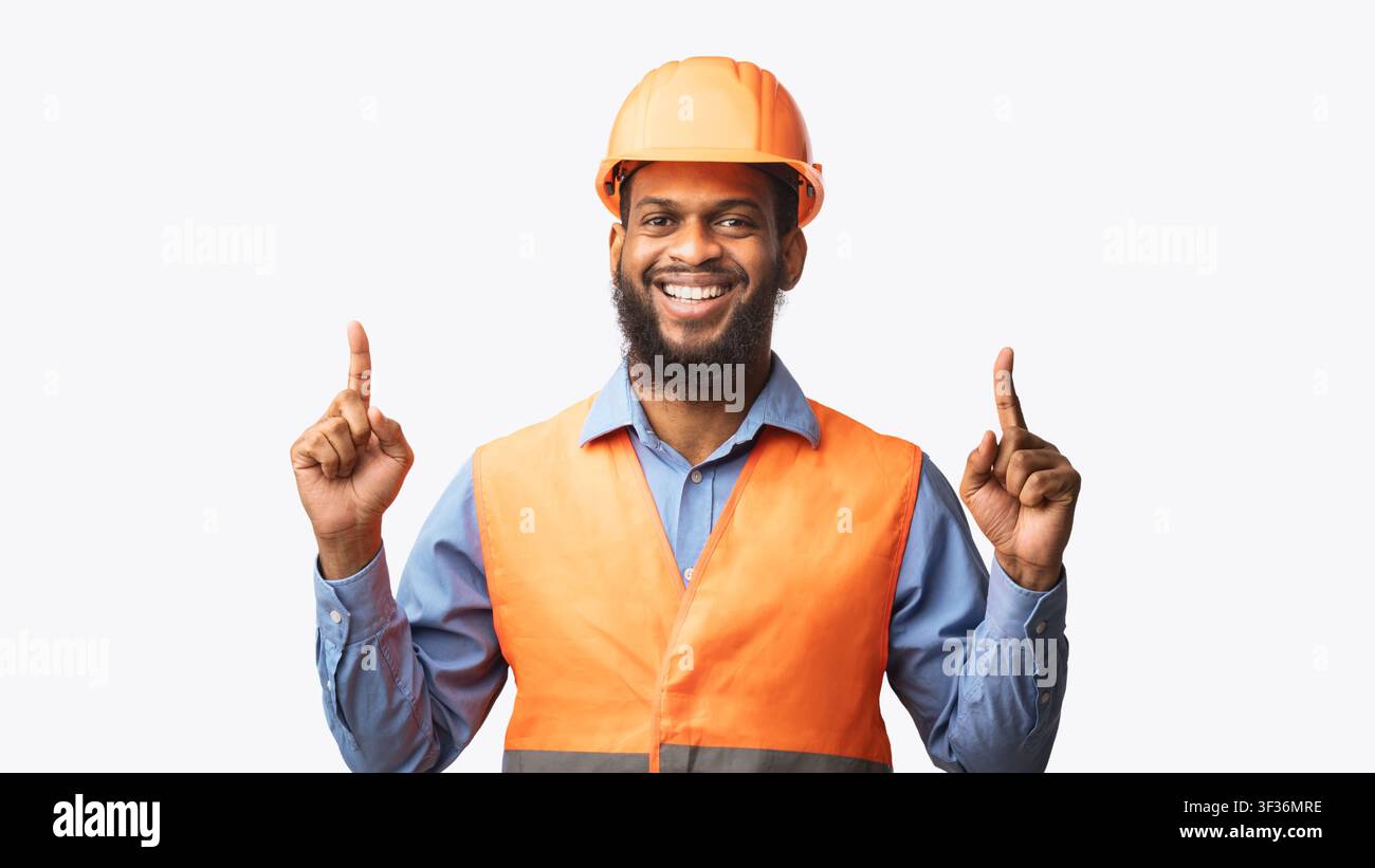 Cheerful Construction Worker Pointing Fingers Up On White Studio Background Stock Photo