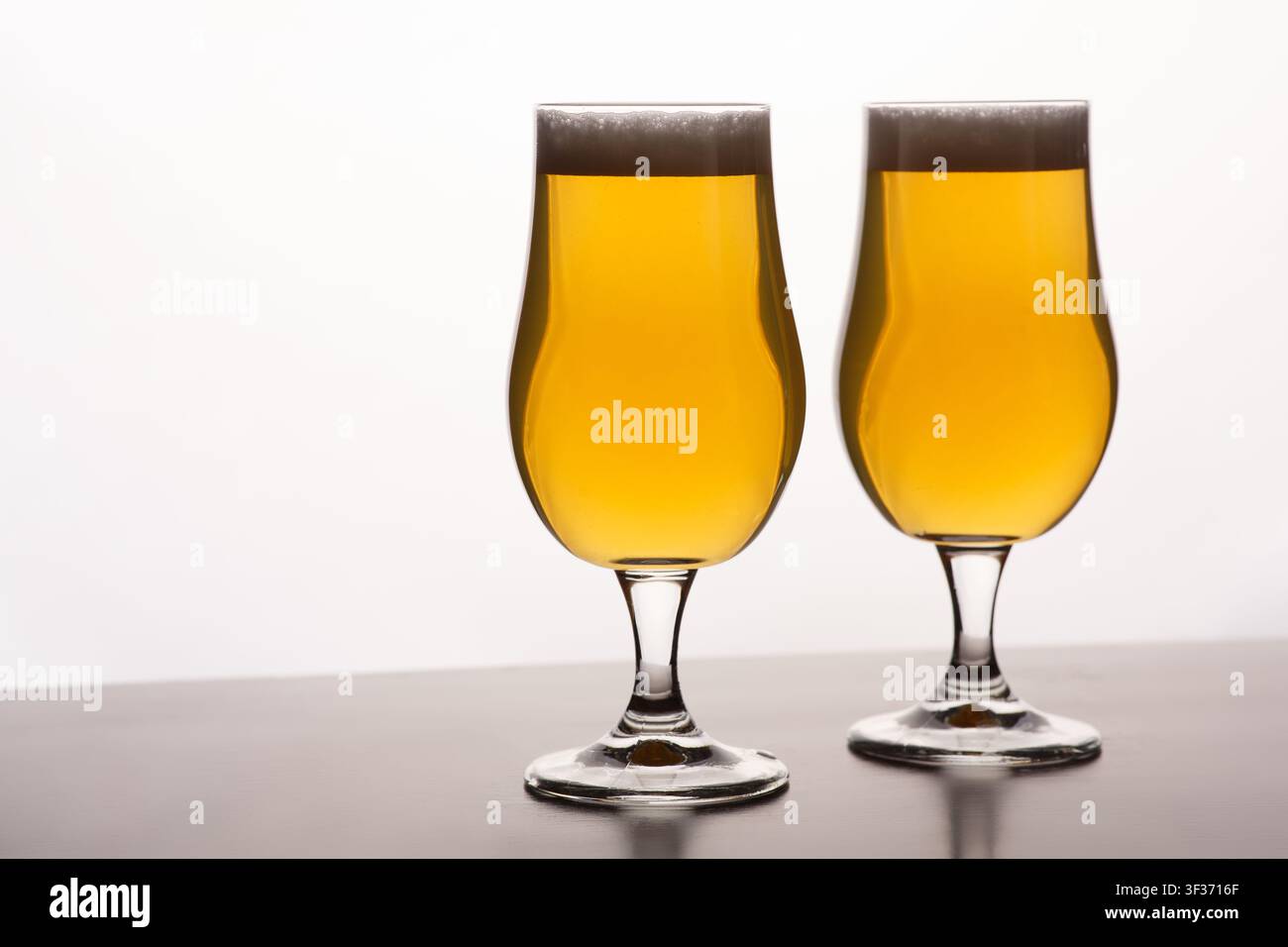 Two glasses of light beer with foam on table and on white background Stock Photo