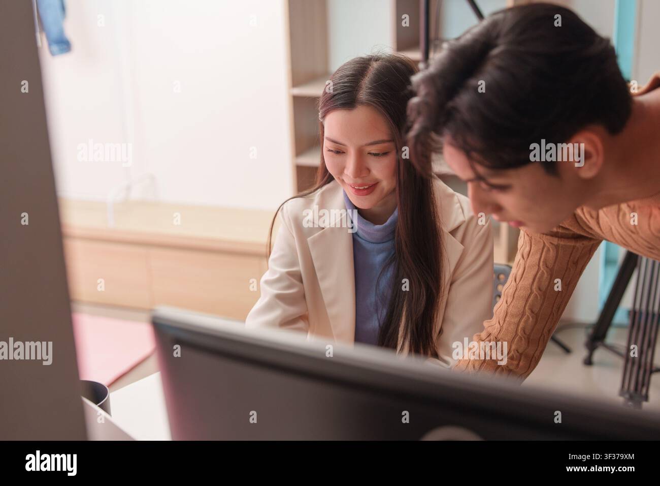 Asian creative professionals collaborating and reviewing project on computer screen Stock Photo