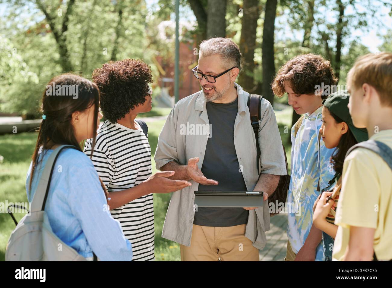 Diverse Teen Students Studying with Teacher in Outdoor Class Stock Photo