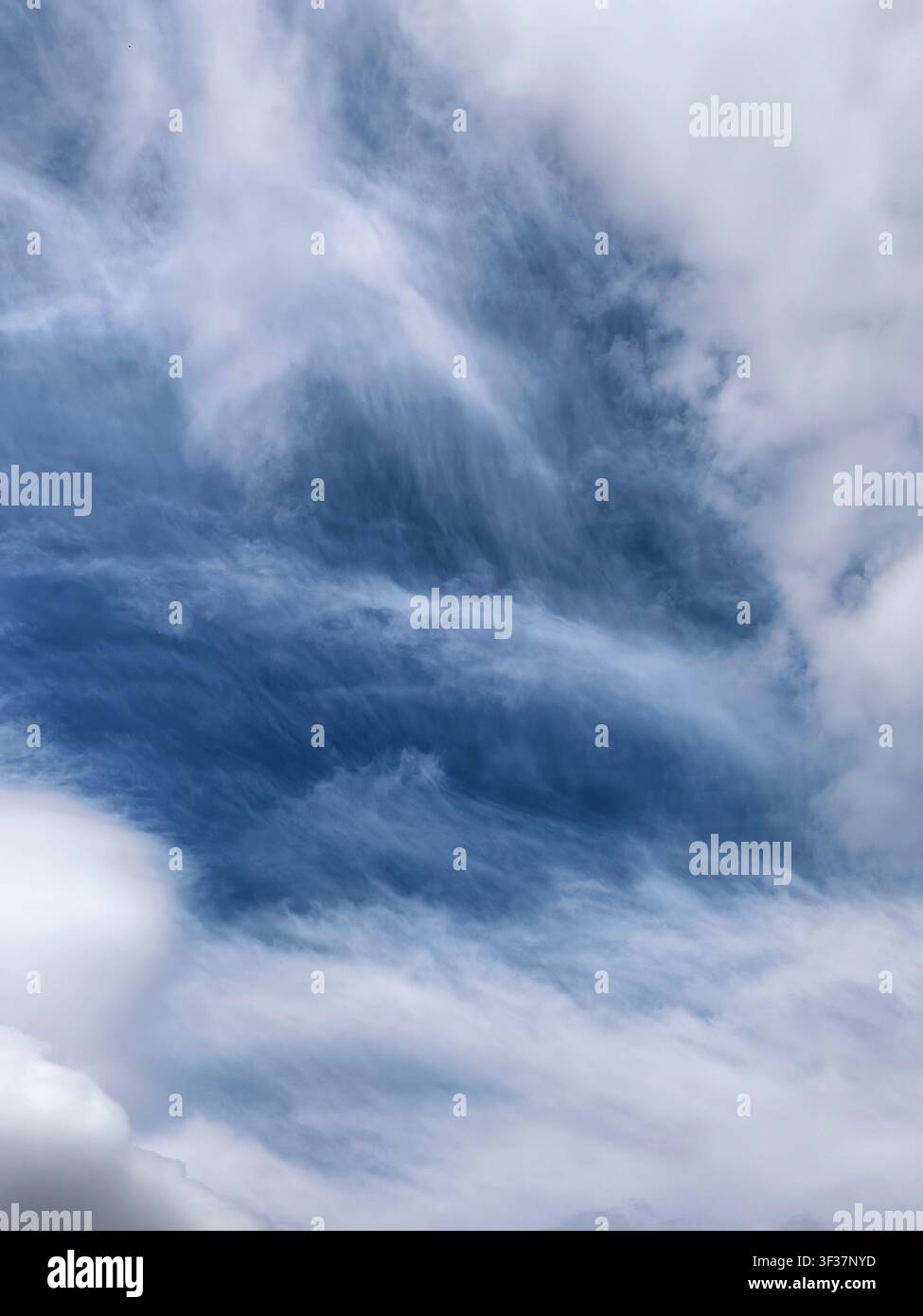 Elegant layered cirrus clouds sweeping across a vivid blue sky. Natural atmospheric background with flowing cloud textures and dramatic visual pattern Stock Photo