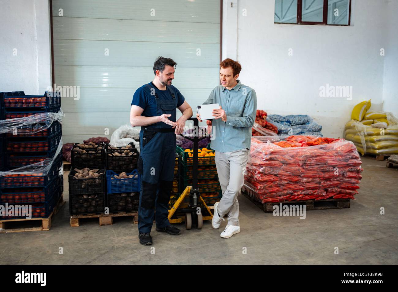 Warehouse workers discussing logistics and inventory on digital tablet Stock Photo