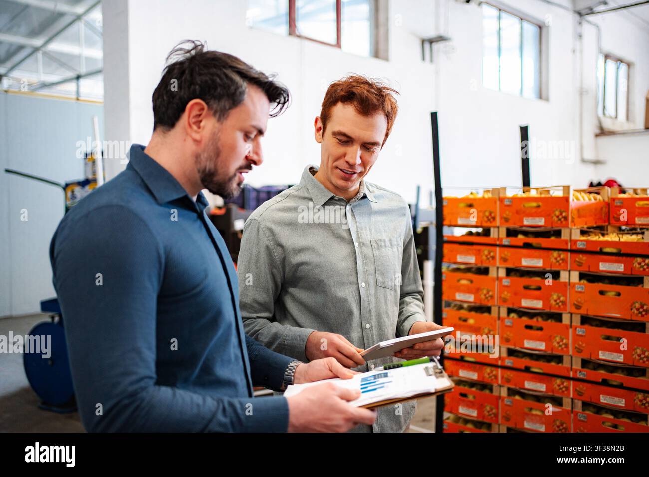 Businessmen checking inventory using clipboard and tablet in warehouse Stock Photo