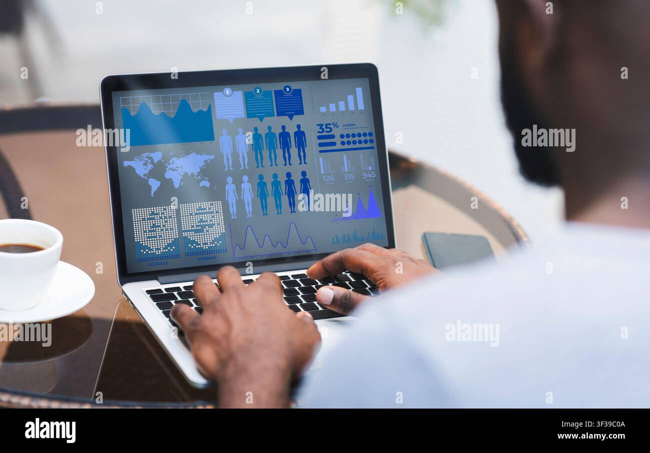 Man working on laptop with graphics and charts on screen Stock Photo