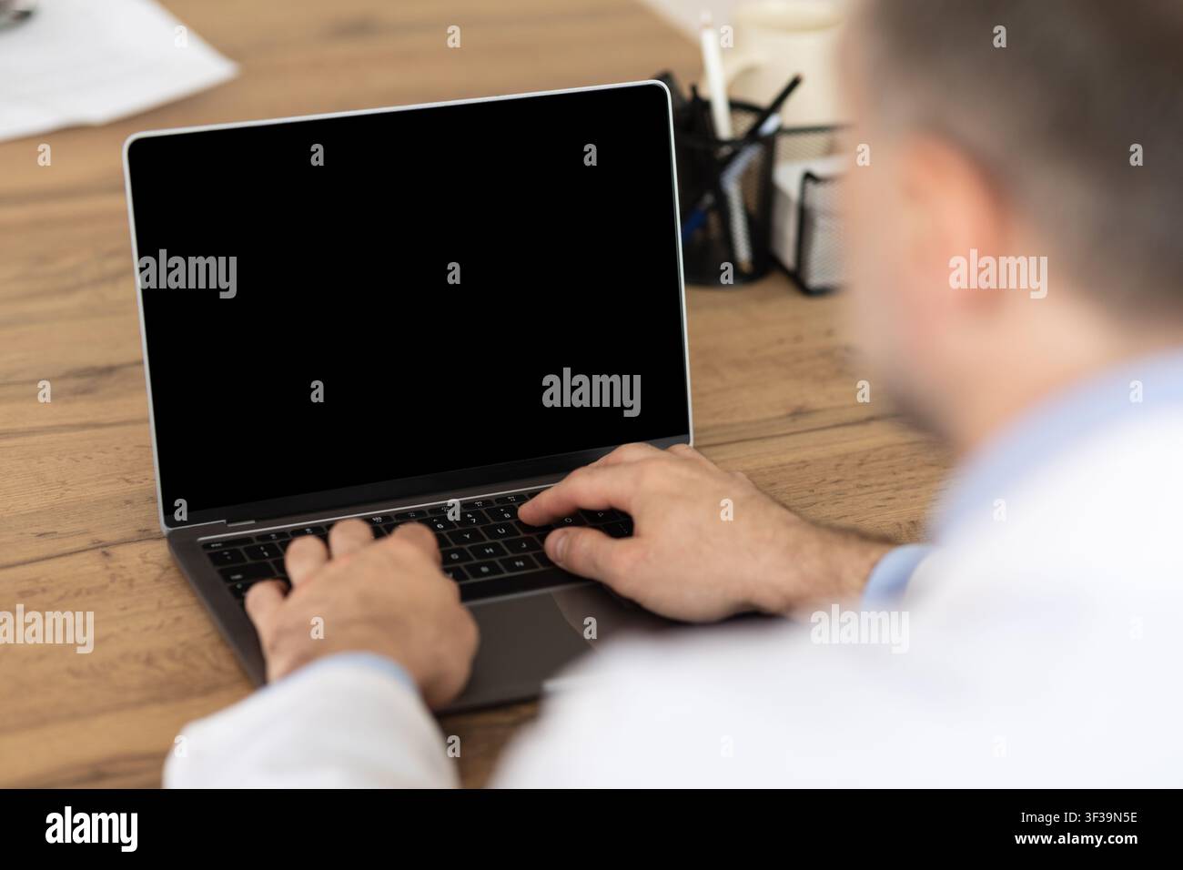 Man working on computer with empty black screen for mockup Stock Photo