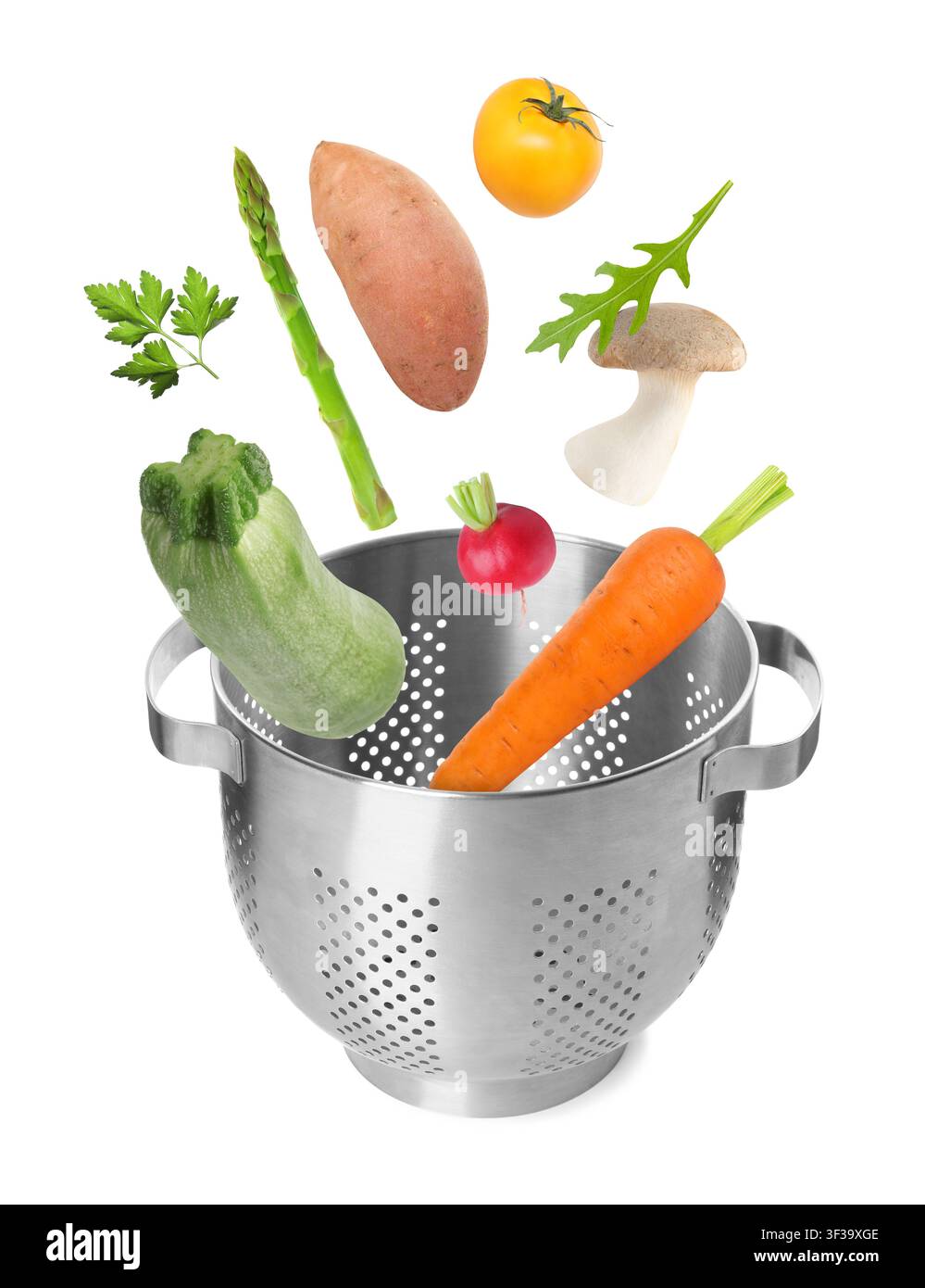 Fresh vegetables falling into colander on white background Stock Photo