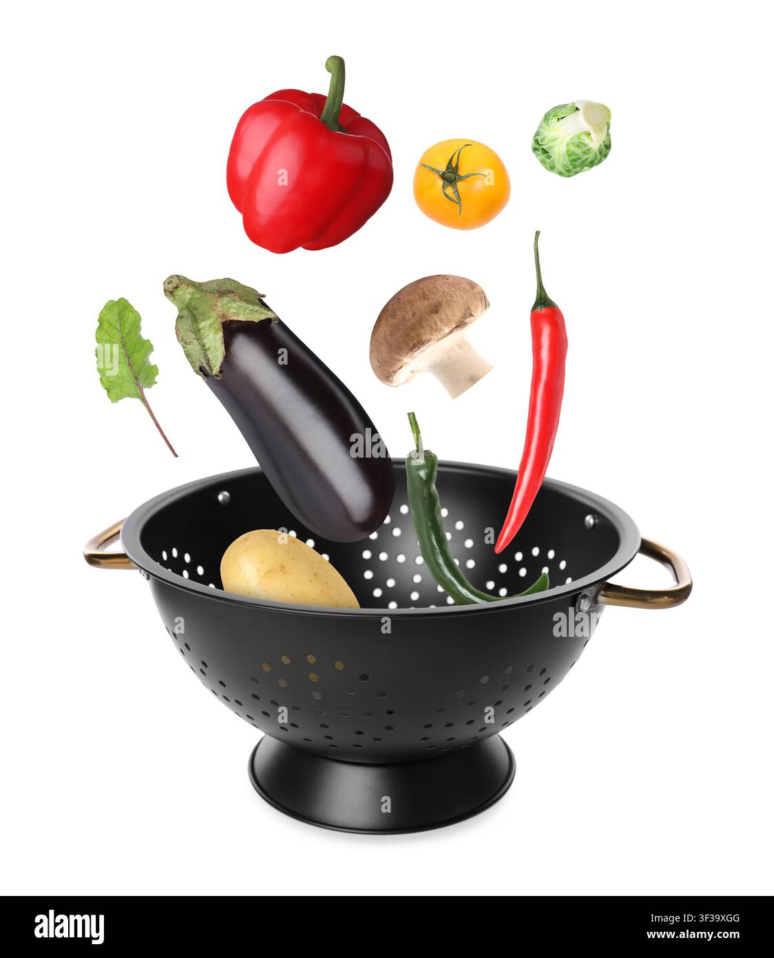 Fresh vegetables falling into colander on white background Stock Photo