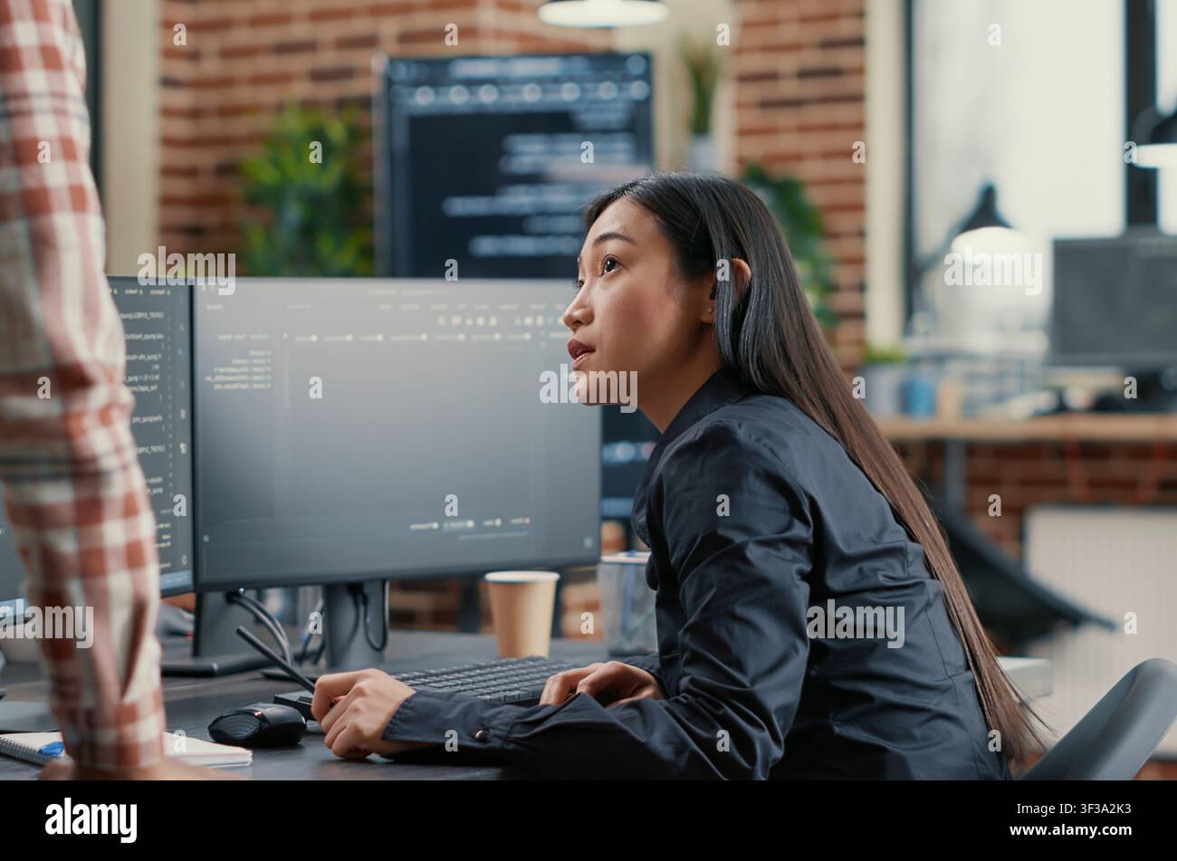 Database developer points a pencil at a computer screen while explaining a compiling algorithm to a coworker during a software team project. Stock Photo